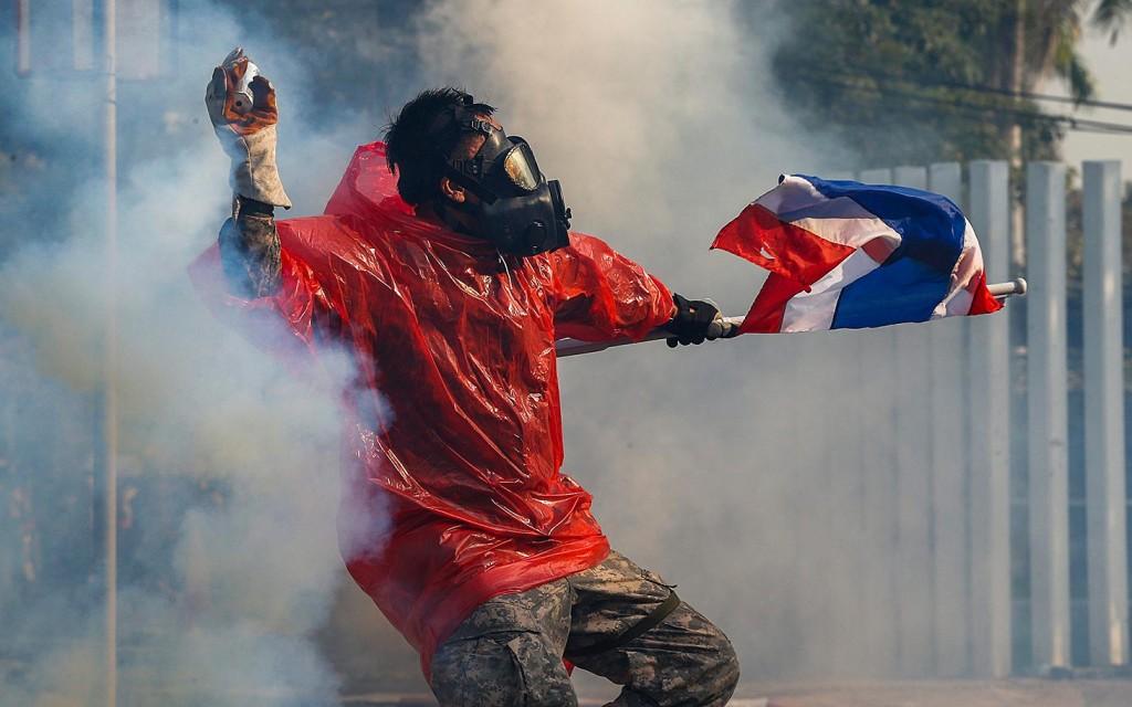 Some+protests+in+Thailand+have+turned+violent.+A+man+throws+a+tear+gas+canister+back+at+the+police.+